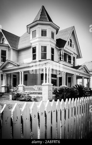 Un iconico white Picket Fence circonda un imponente stile Queen Anne Victorian House, costruita nel 1890, ora una ditta di legge, in Hattiesburg MS, USA, B & W Foto Stock