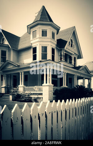 Un iconico white Picket Fence circonda un imponente stile Queen Anne Victorian House, costruita nel 1890, ora una ditta di legge, in Hattiesburg MS, USA, B & W Foto Stock