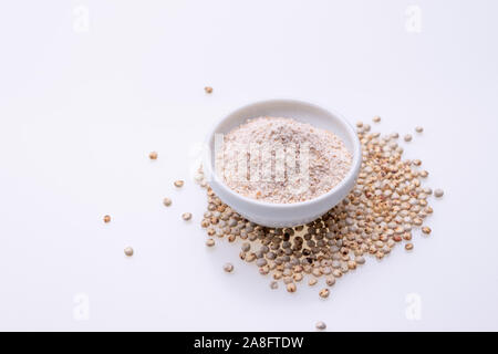 Non cotti materie Sorgo Farina (noto anche come sorgo) in una ciotola bianco, isolato su sfondo bianco Foto Stock