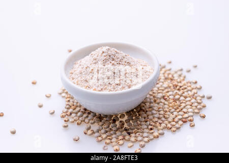 Non cotti materie Sorgo Farina (noto anche come sorgo) in una ciotola bianco, isolato su sfondo bianco Foto Stock