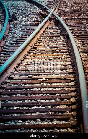 Una vista verso il basso di un treno via la curvatura e divergenti tra loro in corrispondenza di una forcella nelle piste di routing in un atmosfera isolata Foto Stock