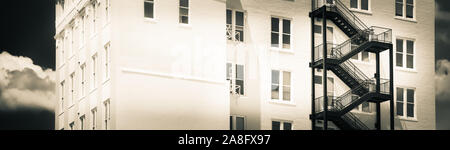 Un contrasto tra un moderno black iron fire escape su un vintage edificio di mattoni bianchi in Hattiesburg MS, STATI UNITI D'AMERICA, in un formato panoramico Foto Stock