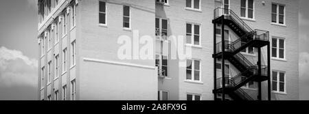 Un contrasto tra un moderno black iron fire escape su un vintage edificio di mattoni bianchi in Hattiesburg MS, STATI UNITI D'AMERICA, in un formato panoramico Foto Stock