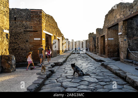 I cani e i visitatori a Pompei Via dell'Abbondanza, uno dei principali asfaltate strade di pietra di età romana antica città. Pompei, Italia, Ottobre 2019 Foto Stock