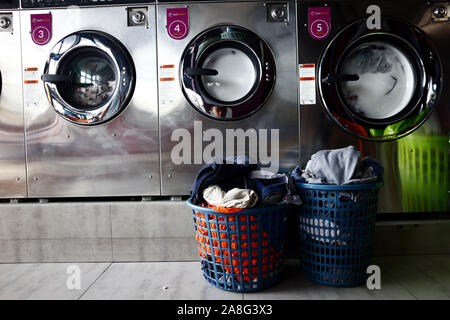ANTIPOLO City, Filippine - 2 Novembre 2019: vestiti sporchi in un cestello di vestiti di fronte a righe di macchine di lavaggio all'interno di una lavanderia a gettoni. Foto Stock