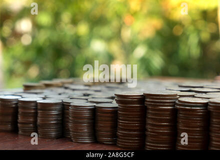 Molte monete in pila sulla scrivania in legno texture di sfondo, il denaro per la pianificazione delle attività di business e di investimento Concetto di risparmio Foto Stock