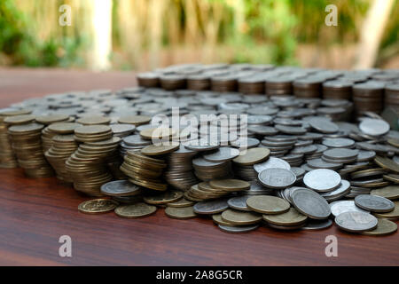 Molte monete in pila sulla scrivania in legno texture di sfondo, il denaro per la pianificazione delle attività di business e di investimento Concetto di risparmio Foto Stock
