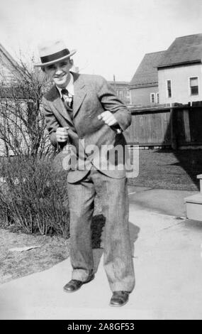 Un dapper giovane uomo in una tuta fingere di essere la foratura per un ritratto nel cortile, ca. 1930. Foto Stock