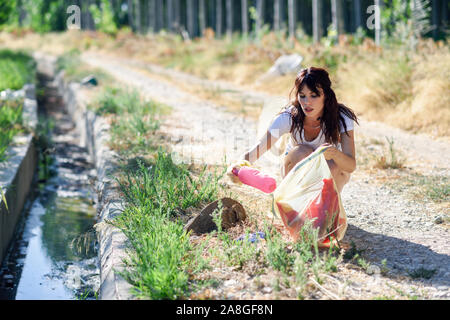 Donna lato raccogliere rifiuti dell'erba in campagna Foto Stock