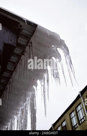 Lunga e affilata ghiaccioli sul tetto. Pericolo per le persone. Foto Stock