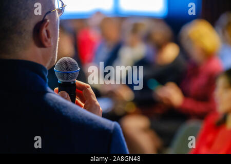 Presentatore maschio parla al pubblico in officina Foto Stock