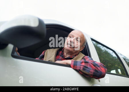 Senior vecchio uomo ispanico guardando fuori di automobile che è triste e irritati a causa di inceppamenti di traffico Foto Stock