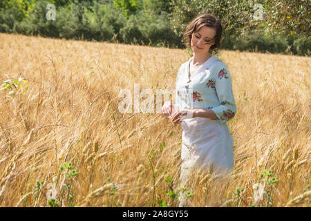 Donna sognante nel 40s vestiti in un campo di grano Foto Stock
