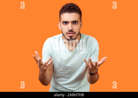 Cosa vuoi fare? Ritratto di scontento infastiditi brunette uomo con la barba in casuale t-shirt bianco in piedi con le mani alzate, mad indignati expression Foto Stock