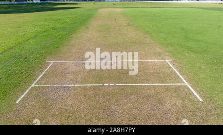 Scenic cricket motivi dal bianco recinzione perimetrale del campo di erba astro e campo di erba mattina summer blue giorno paesaggio di campagna. Foto Stock