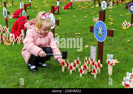 09 novembre 2019, Glasgow, Scotland, Regno Unito. Grazia EVERETT (dai 3 anni) da Glasgow assiste alla British Legion Giardino della Rimembranza in George Square, da Glasgow a lasciare il papavero su piccole croci di legno in ricordo del suo bisnonno 'CHARLES EVERETT' che hanno servito nella RAF, il suo bisnonno "Robert" di pietra che ha servito con il Royal Engineers e il Cameronians e suo zio "Alex" di pietra che ha servito con il Royal Highland Fusiliers. Credit Findlay/ Alamy News Foto Stock