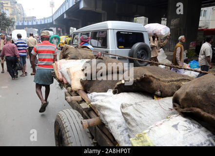 Lavoro duro indiani spingendo il carico pesante attraverso strade di Calcutta, in India Foto Stock