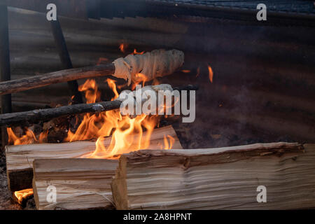 Due Bannocks oltre il fuoco su un bastone Foto Stock
