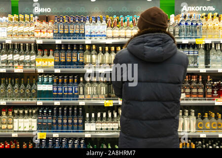 Ekaterinburg, Russia - Novembre 2019. Un uomo di fronte le righe di alcool nel mercato. Il compratore seleziona il prodotto Foto Stock