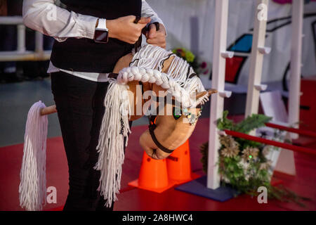 Mosca, Russia. 7 Novembre, 2019 partecipanti del Festival Hobbyhorsing nel club equestre "Izmailovo' durante la formazione prima del concorso di Mosca, Russia. Sport Hobbyhorsing simula tradizionali eventi equestri tra cui competono in dressage e show jumping dalla sella di un cavallo immaginario Foto Stock