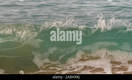 Onde che si infrangono su una spiaggia tropicale, belle acque turchesi e gocce Foto Stock