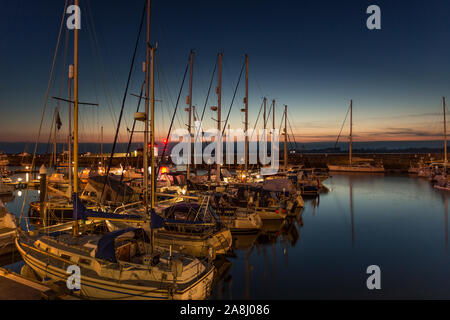 Yacht ormeggiati nel Victoria Dock a Caernarfon al tramonto sulla costa settentrionale del Galles Foto Stock