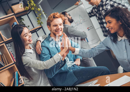 Startupers lavorando insieme a Office dando alta cinque allegro Foto Stock