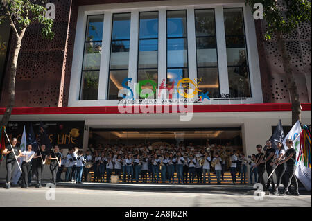 Un gruppo di ballerini con bandiere e membri dell'orchestra sono visti di fronte alla facciata del teatro come essi rappresentano per i media durante una parata promozionali di 'un Chorus Line' musical diretto dallo spagnolo attore e regista Antonio Banderas, precedendo la premiere al Soho Caixabank teatro il 15 novembre 2019. 'Un Chorus Line" è il nuovo musical di Antonio Banderas circa un gruppo di danzatori provenienti da Broadway che fanno parte di un coro musicale. Foto Stock