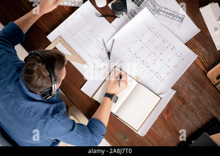 Vista dall'alto di ingegnere professionale con i notebook e matita rendendo note di lavoro Foto Stock