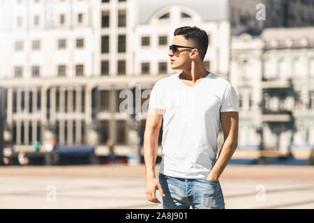 Per il tempo libero all'aria aperta. Elegante ragazzo in occhiali da sole permanente sulla strada mano in tasca cercando in disparte pensieroso Foto Stock