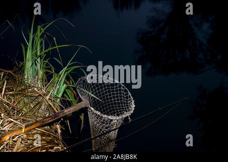 Vintage rete da pesca sulle sponde del fiume di notte. Il simbolo della pesca. Foto Stock