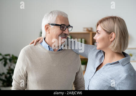 Felice uomo maturo e la sua giovane figlia abbracciando e guardando ogni altro Foto Stock