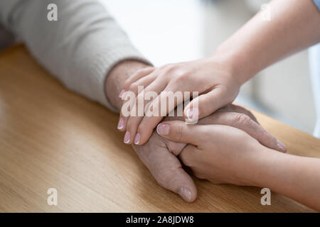 Le mani del giovane affectionae e donna attenta holding che del suo padre senior Foto Stock