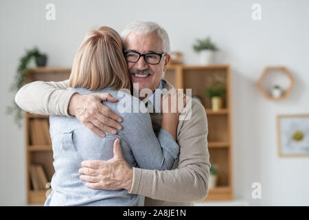 Felice e commosso senior uomo dando abbraccio a sua bionda giovane figlia Foto Stock