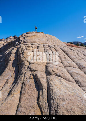 Escursionista in cima a una manopola di arenaria, Flusso di Lava Trail, Snow Canyon State Park, Saint George, Utah. Foto Stock