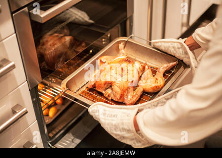 La donna la cottura di pollo arrosto in un forno Foto Stock