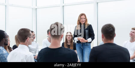 Giovane donna conduce attività di formazione con un gruppo di giovani. Foto Stock