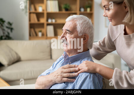 Malati pensionati uomo con i capelli grigi tenendo la mano della sua giovane figlia attenta Foto Stock