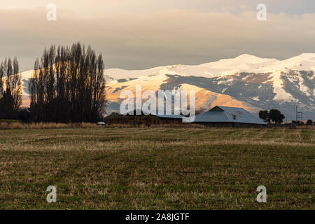 Vista panoramica di una fattoria al tramonto contro innevate montagne delle Ande Foto Stock