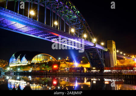 Il Quayside a Newcastle e Gateshead di notte, guardando al di là del Fiume Tyne sotto il Tyne Bridge verso la Sage music center. Foto Stock