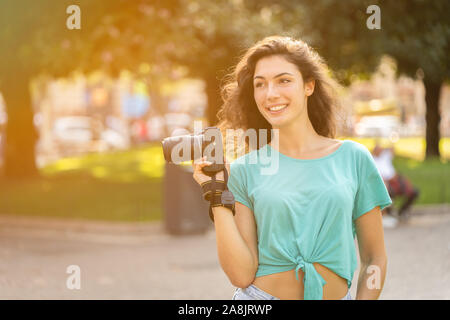 Sorridente giovane donna di scattare le foto in città Foto Stock