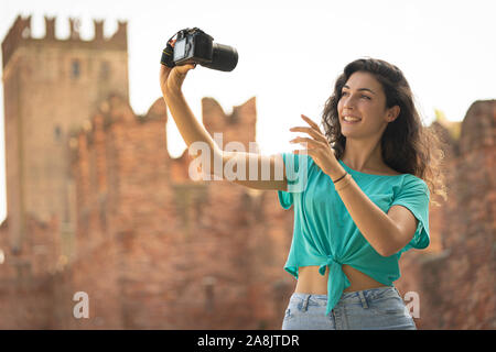 Ragazza tenendo un selfie con una grande fotocamera, vecchia tecnologia Foto Stock