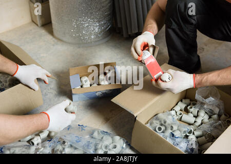 I lavoratori stanno controllando il set completo di raccordi per l'installazione di riscaldamento domestico. Foto Stock