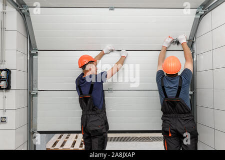 I lavoratori sono l'installazione di porte di sollevamento del garage. Foto Stock