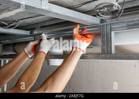 I lavoratori sono il montaggio di una trama complessa per muro a secco del soffitto. Foto Stock