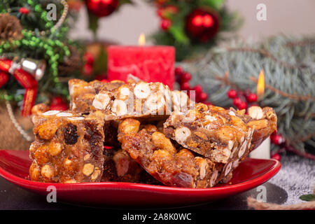 Italiani dolci noci, nocciole, mandorle, fichi, dolce al miele sulla piastra di rosso Foto Stock