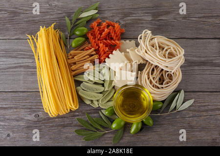 Diversi tipi di pasta sullo sfondo di legno. Spaghetti. Olio d'oliva. Foto Stock