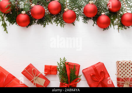 Composizione di Natale fatto di red regali di Natale, rosso ninnolo decorazioni, Abete rami di legno bianco sullo sfondo della tabella. Natale, Natale, inverno Foto Stock