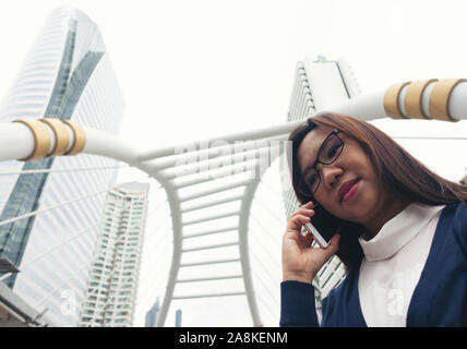 Imprenditrice passeggiate all'aperto e parlando al telefono cellulare Foto Stock