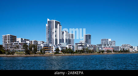 Grandi case di waterfront, appartamento condominiums in comunità suburbane sul porto con viale alberato pedonale, cielo blu in background Foto Stock